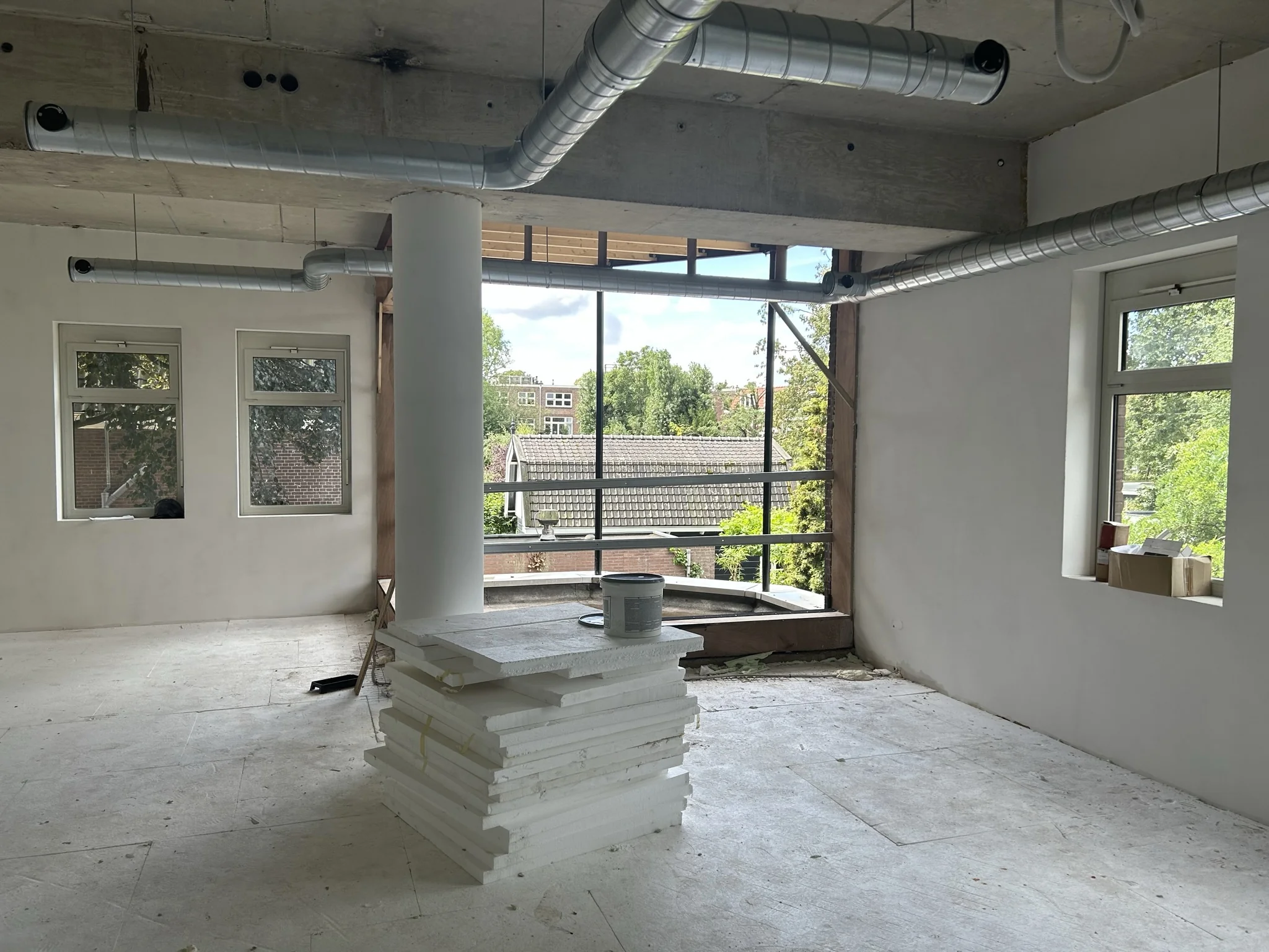 Binnenruimte in verbouwing aan de Bergse Dorpsstraat met zicht op daken en groen buiten.